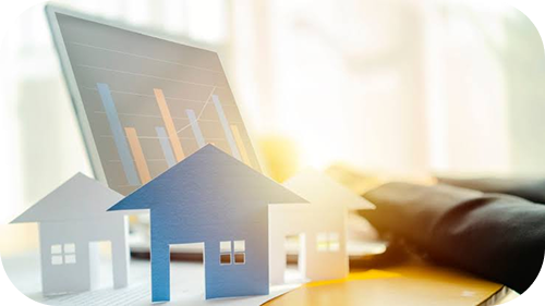 Model houses beside a laptop displaying property market charts